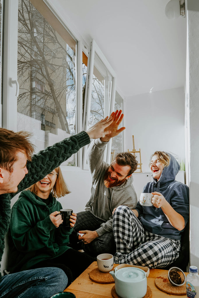 Four friends sit by a window, sharing laughter over coffee