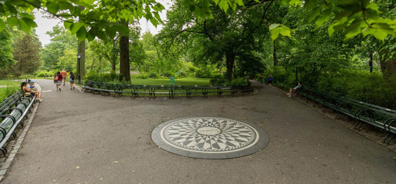 Strawberry Fields in Central Park, New York City. Iconic mosaic surrounded by lush greenery, benches, and pathways.